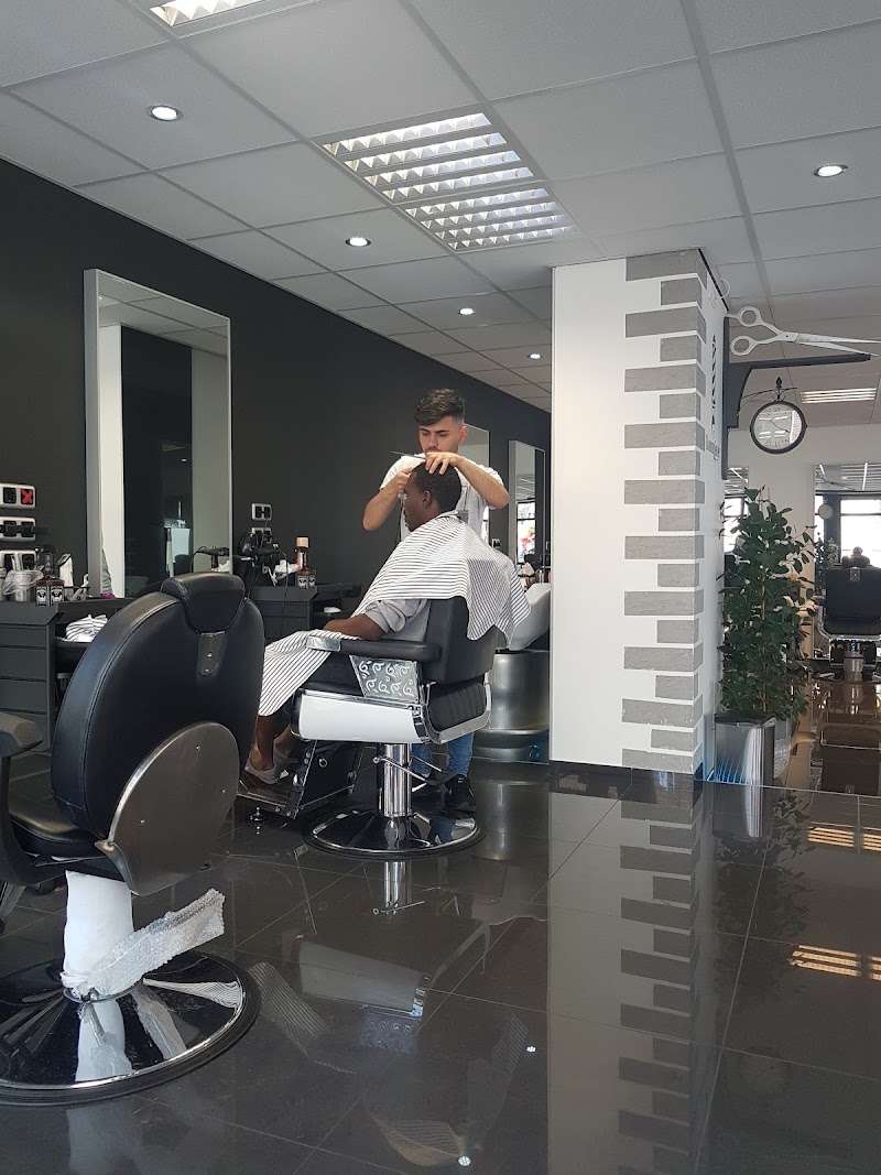 Het interieur: antracieten wanden, een glanzende zwarte tegelvloer en chromen barberstoelen.