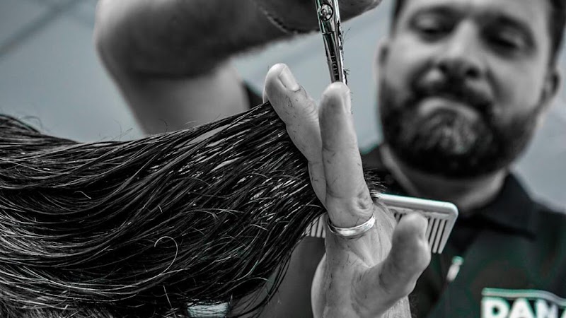 Close-up in zwart-wit: nat haar tussen twee vingers, schaar er middenin, kam in de andere hand.