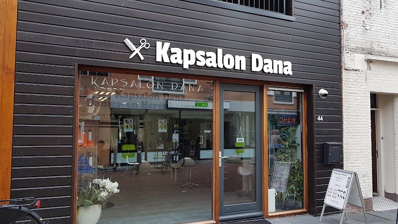 De houten gevel aan de Voorstraat met witte letters Kapsalon Dana en het bord met tarieven op de stoep.